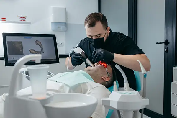 Dentist using a DIAGNOdent pen to detect tooth decay on a patient.